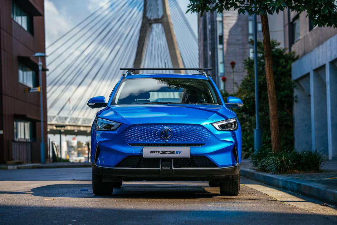 Blue 2022 MG ZS EV parked in city with roof rails front view Blue 2022 MG ZS EV parked in city with roof rails front view