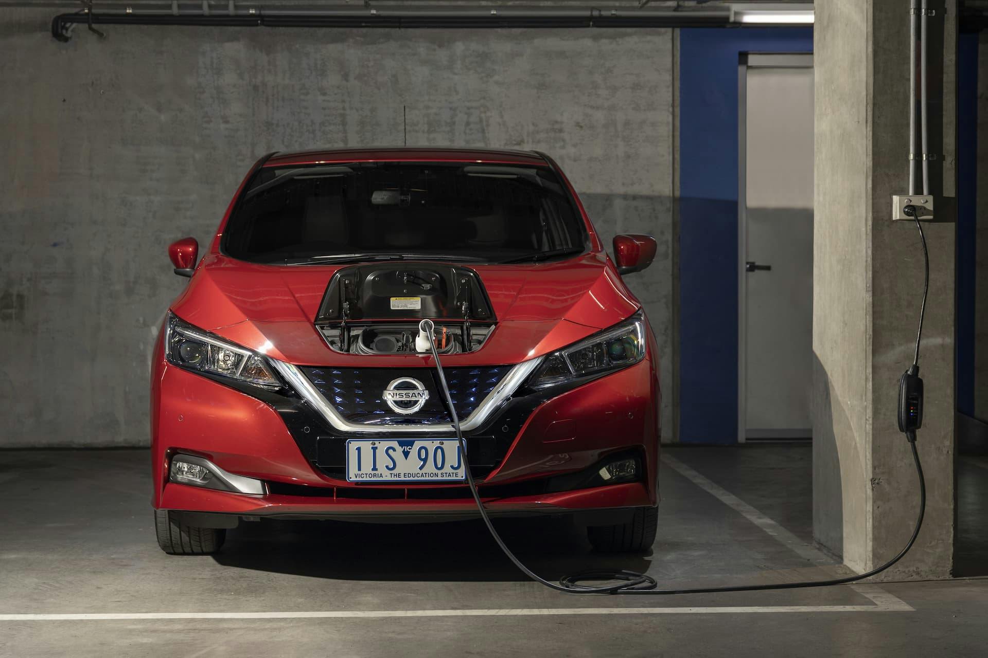 Red Nissan Leaf charging from powerpoint in basement garage