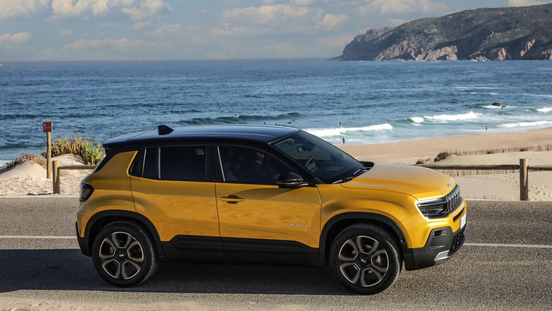 2025 Jeep Avenger in gold side view driving with beach background 2025 Jeep Avenger in gold side view driving with beach background