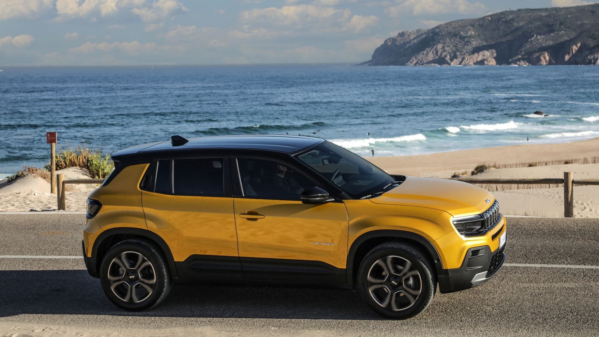 2025 Jeep Avenger in gold side view driving with beach background 2025 Jeep Avenger in gold side view driving with beach background