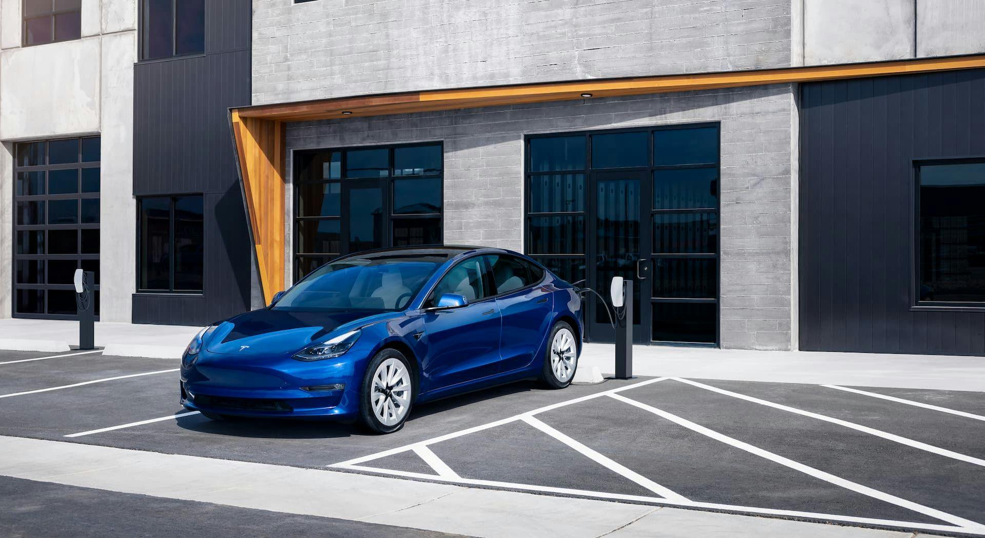 Blue Tesla Model 3 charging at AC Destination charger in commercial complex