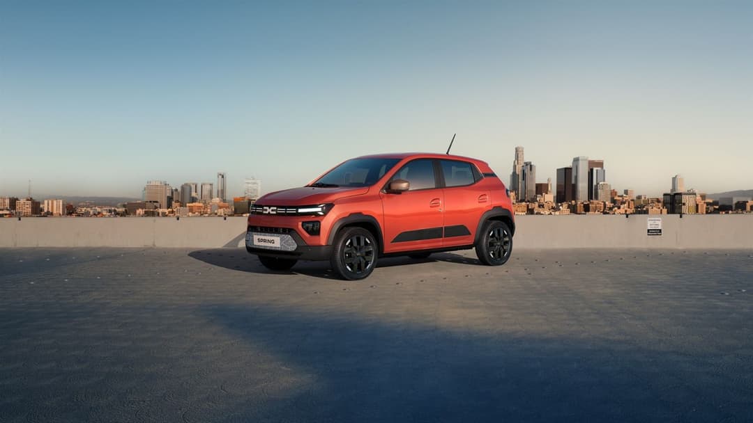 Dacia Spring three quarter view in orange parked with city skyline background Dacia Spring three quarter view in orange parked with city skyline background