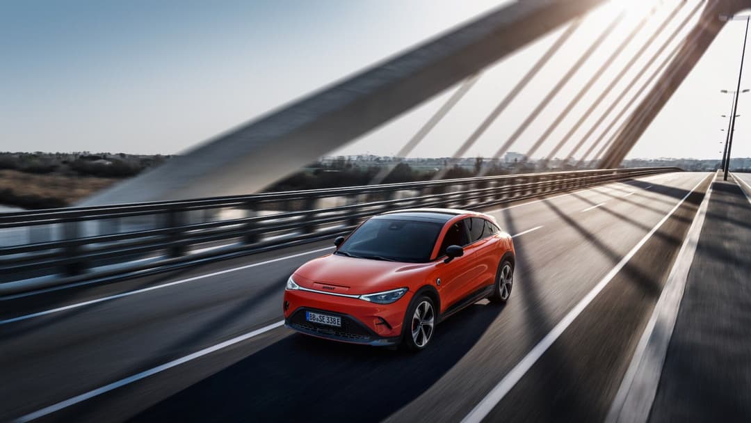 Smart EV in red driving on bridge three quarter view Smart EV in red driving on bridge three quarter view