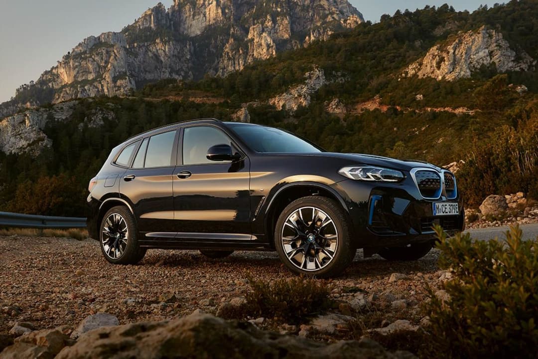 BMW iX3 side view driving off road with mountain background BMW iX3 side view driving off road with mountain background