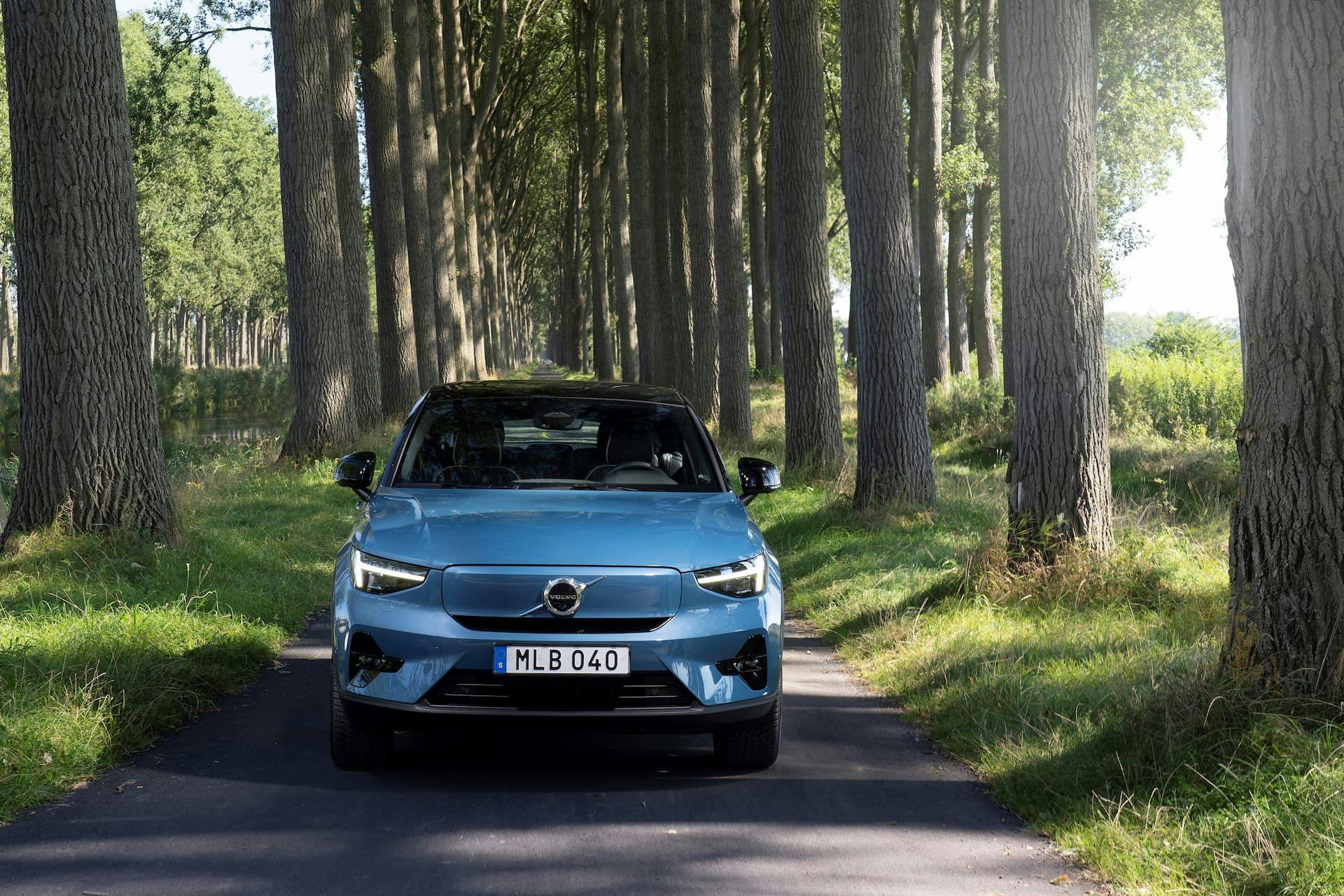 Blue Volvo C40 EV driving in forest