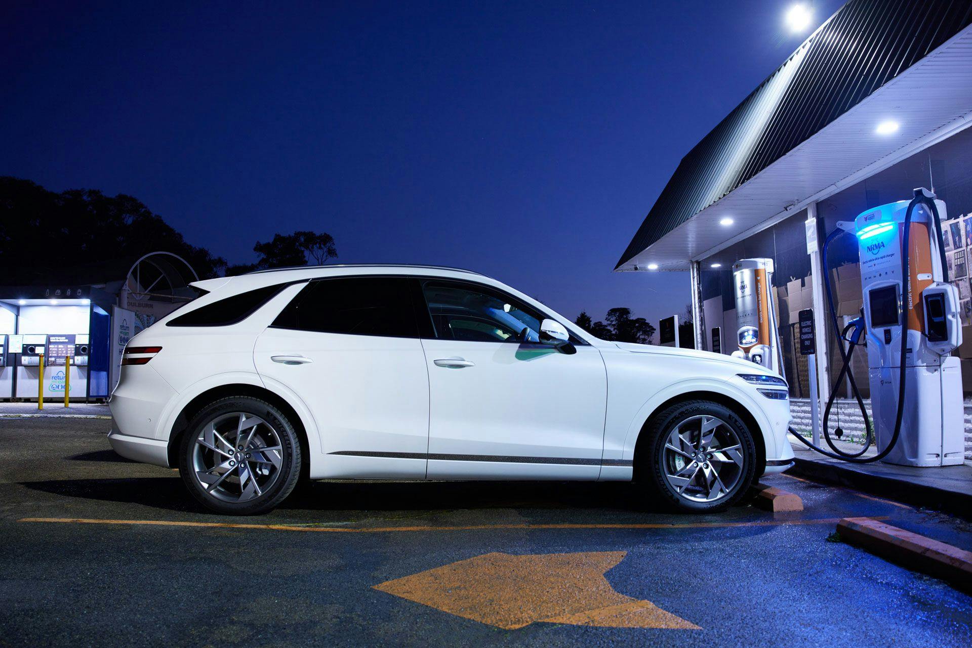 White Genesis Electrified GV70 charging at Chargefox station during night
