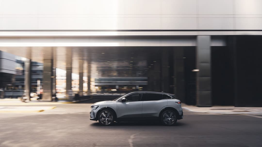 2024 Renault Megane E-Tech in grey driving at city side view 2024 Renault Megane E-Tech in grey driving at city side view