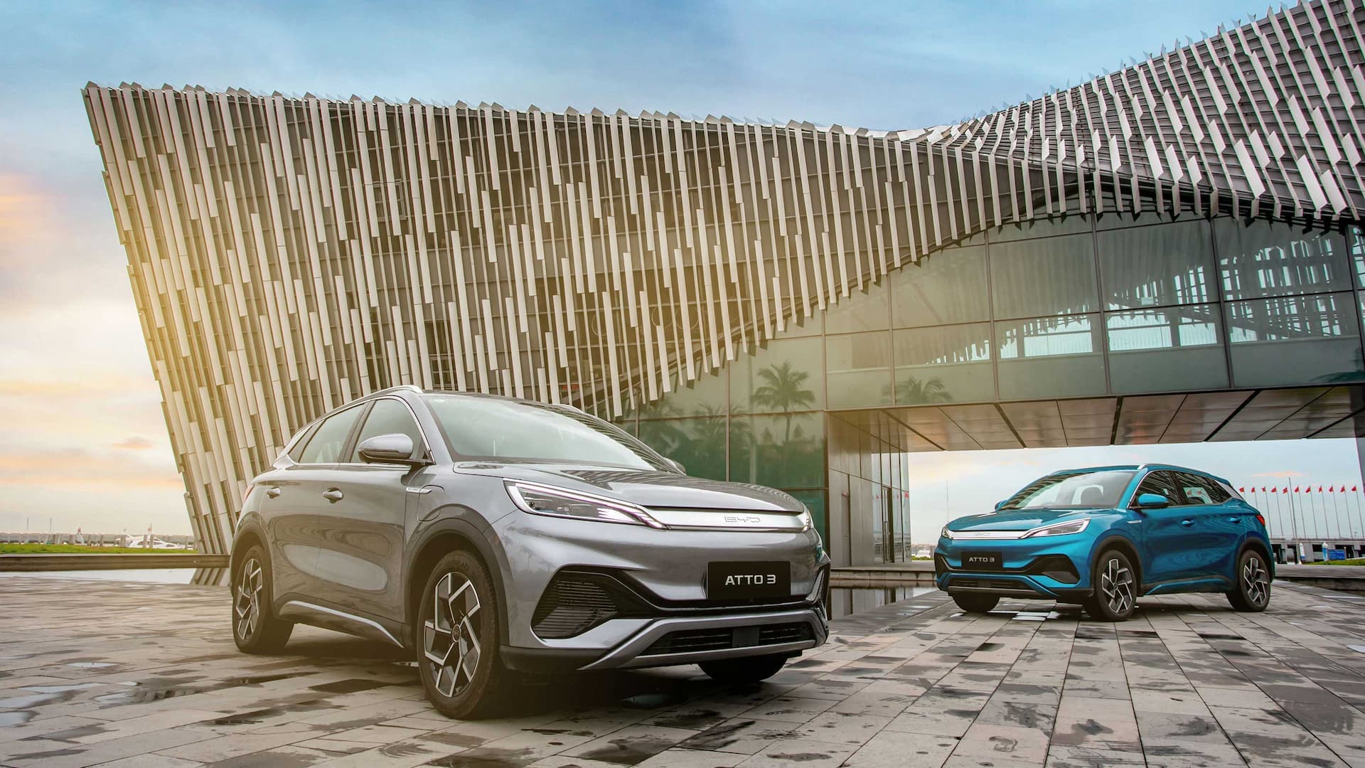 Grey and blue BYD Atto 3 in front of urban building Grey and blue BYD Atto 3 in front of urban building