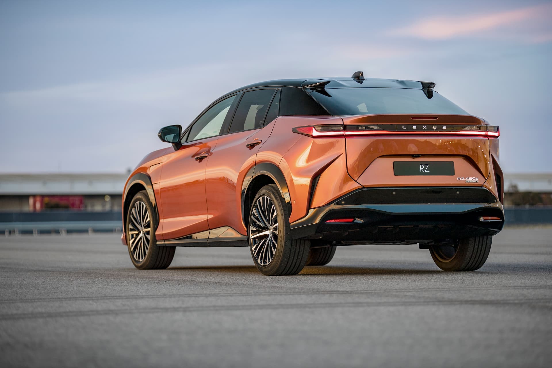 Two-tone copper/black Lexus RZ in sunset rear view with LED tail lights on Two-tone copper/black Lexus RZ in sunset rear view with LED tail lights on