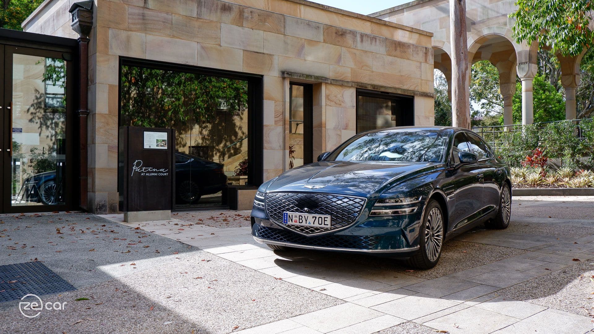 Matira Blue Genesis Electrified G80 in front of mirror reflection and sandstone building Matira Blue Genesis Electrified G80 in front of mirror reflection and sandstone building