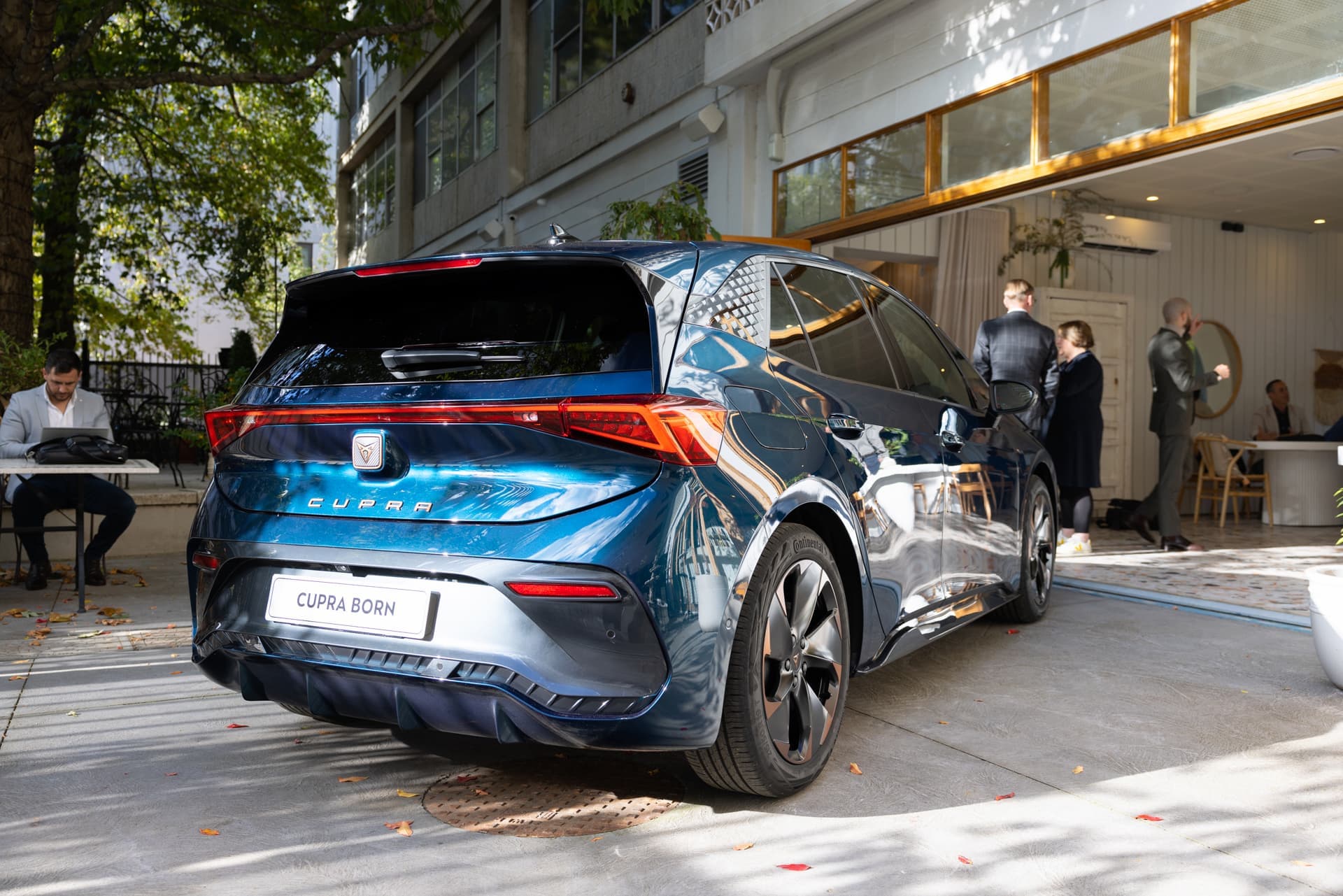 Aurora Blue Cupra Born rear view in front of cafe Aurora Blue Cupra Born rear view in front of cafe