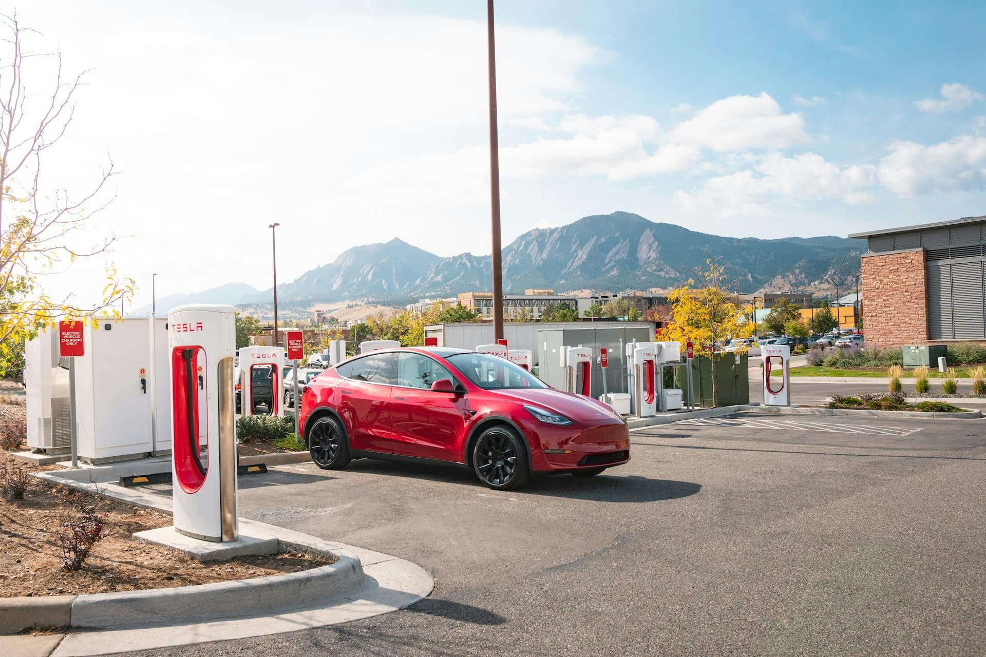 Red Tesla Model Y charging at Supercharging hub