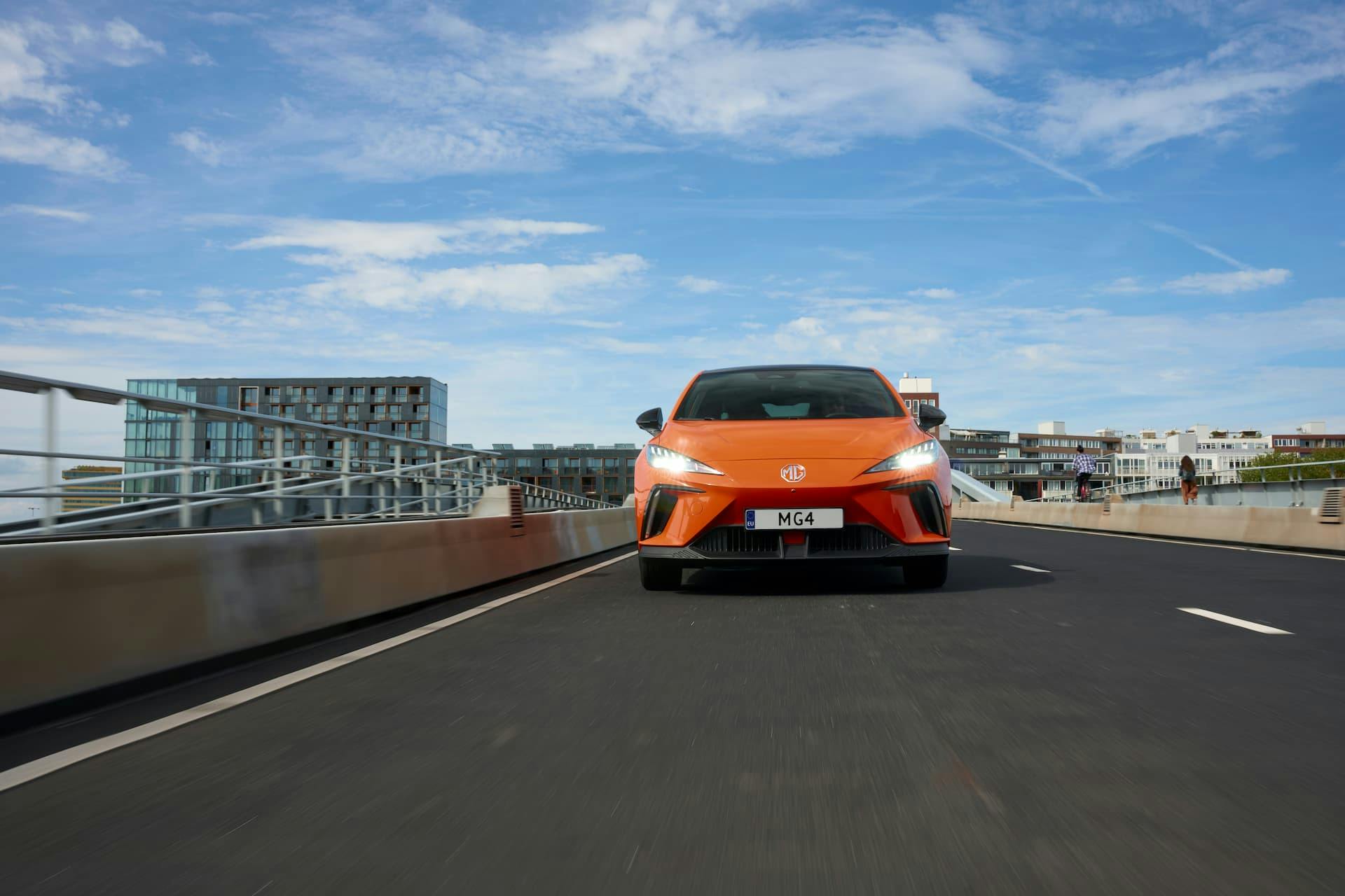 Orange MG 4 driving on bridge front view